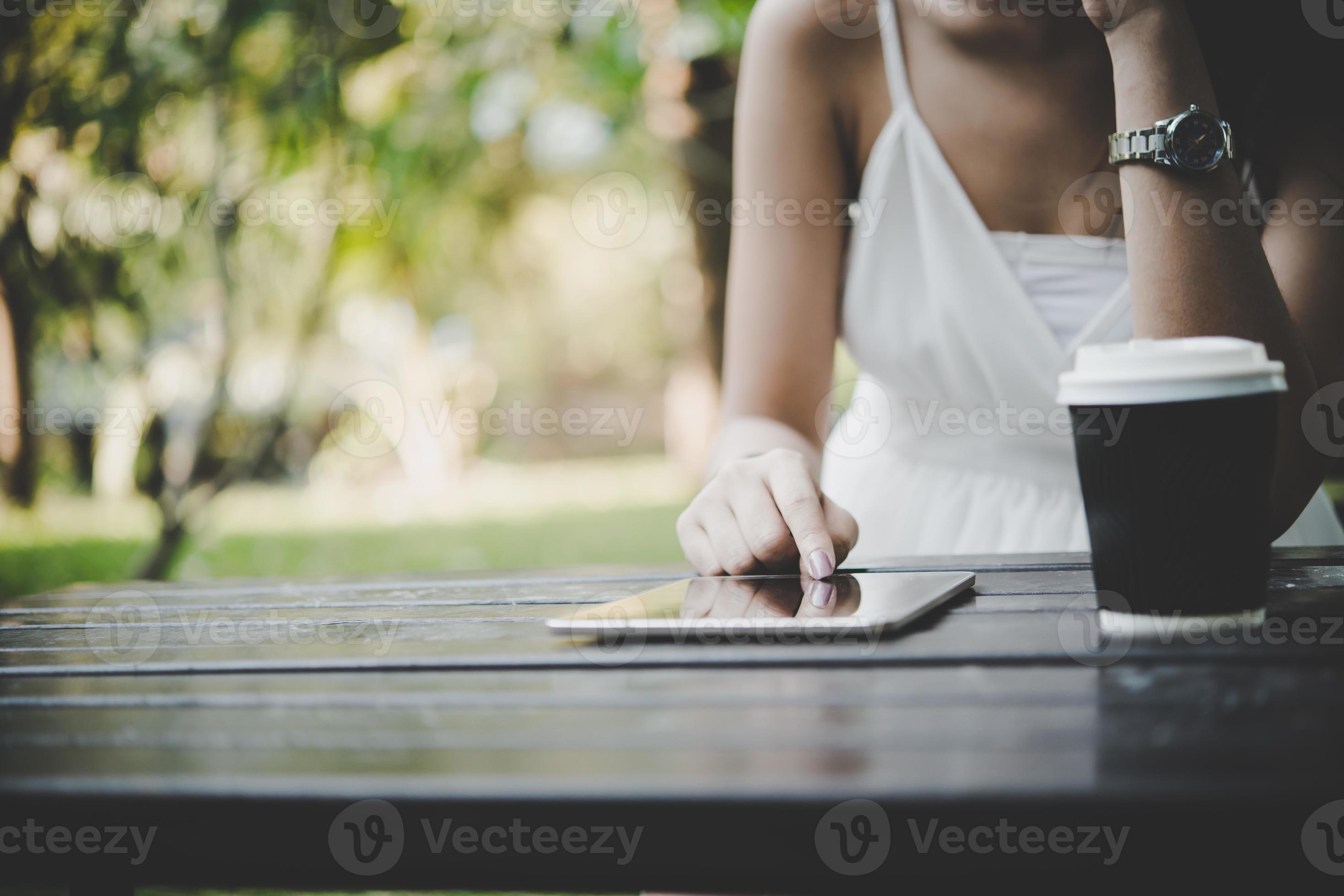 primo piano della donna che tiene computer tablet sul tavolo di legno con una tazza di caffè foto