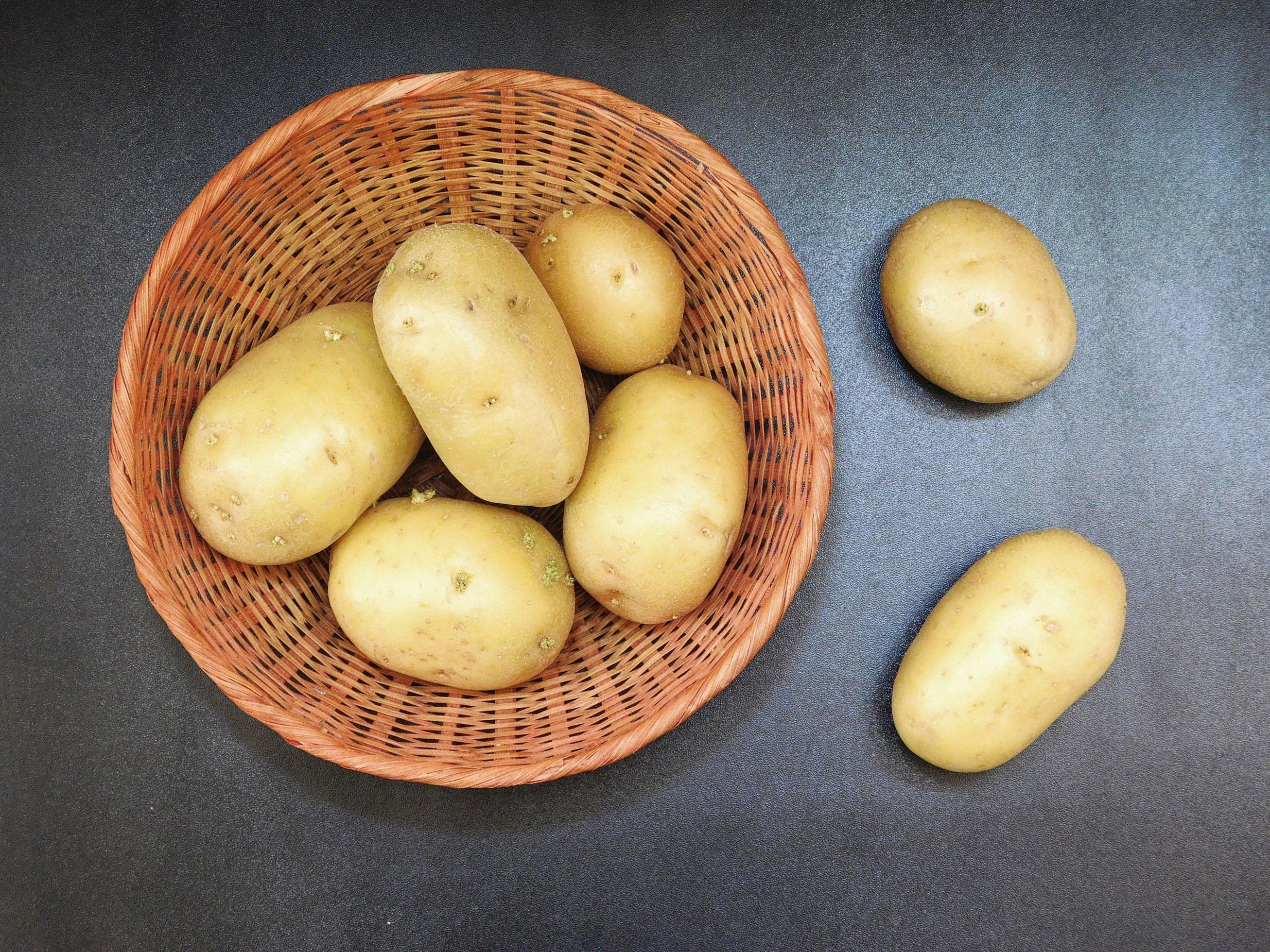 patate in un cesto di vimini su uno sfondo di tavolo scuro foto