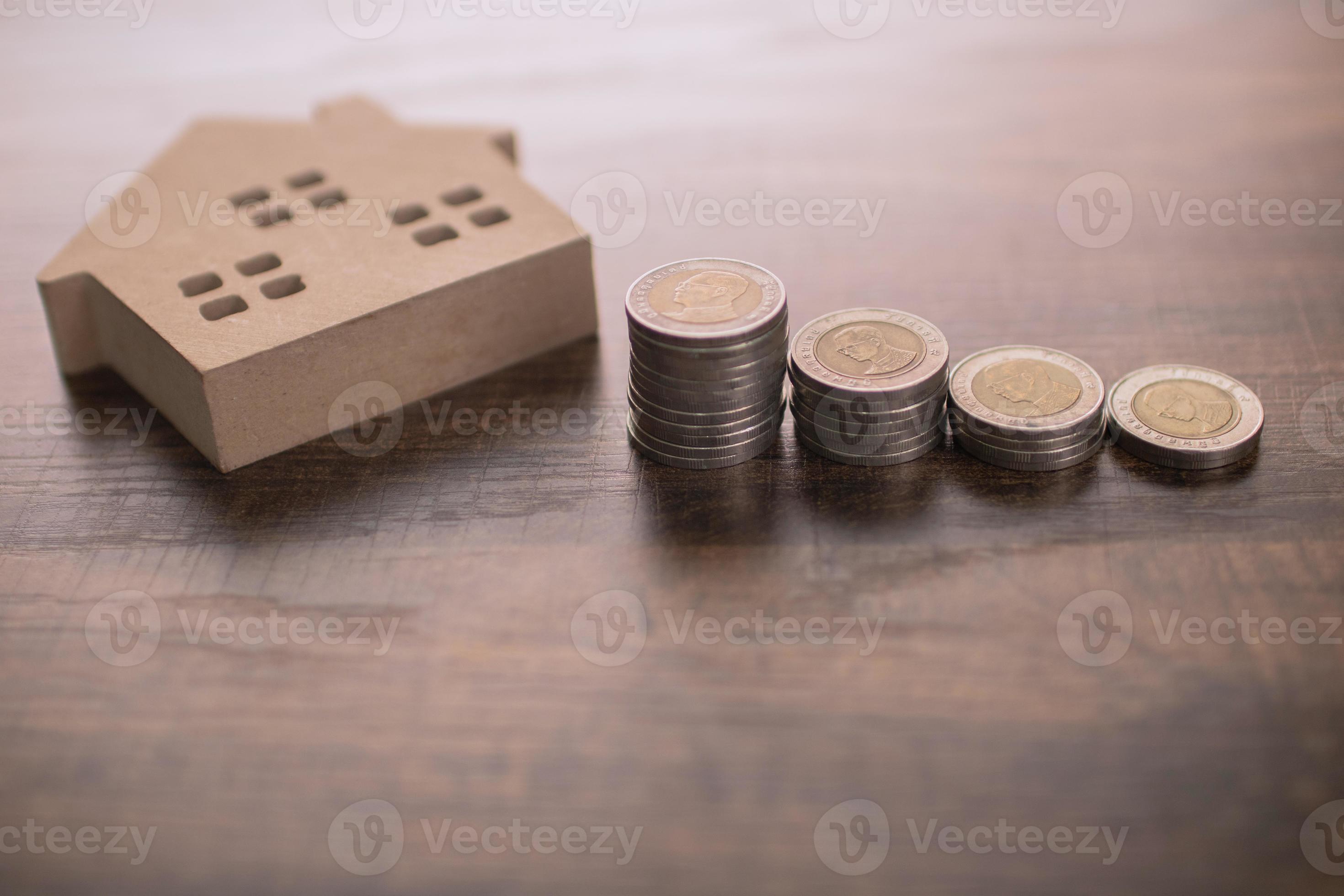 modello di piccola casa in legno sul tavolo con monete foto