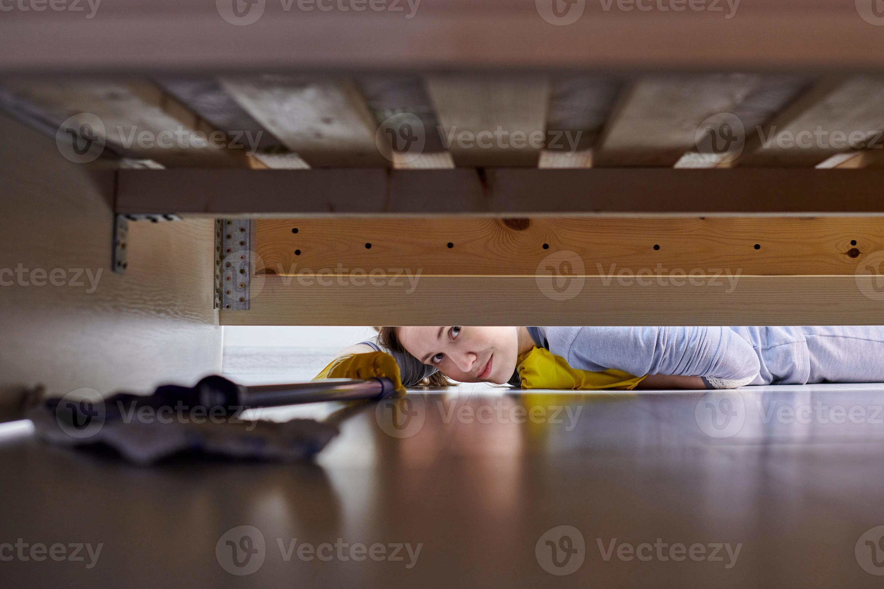 donna pulizia pavimento sotto letto utilizzando piatto bagnato