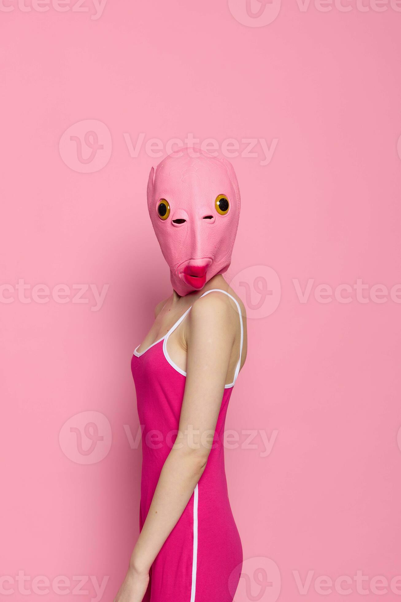 donna nel un' pesce costume per Halloween pose contro un' rosa sfondo nel  un' pazzo pauroso costume con un' rosa silicone maschera su sua testa  23686945 Stock Photo su Vecteezy