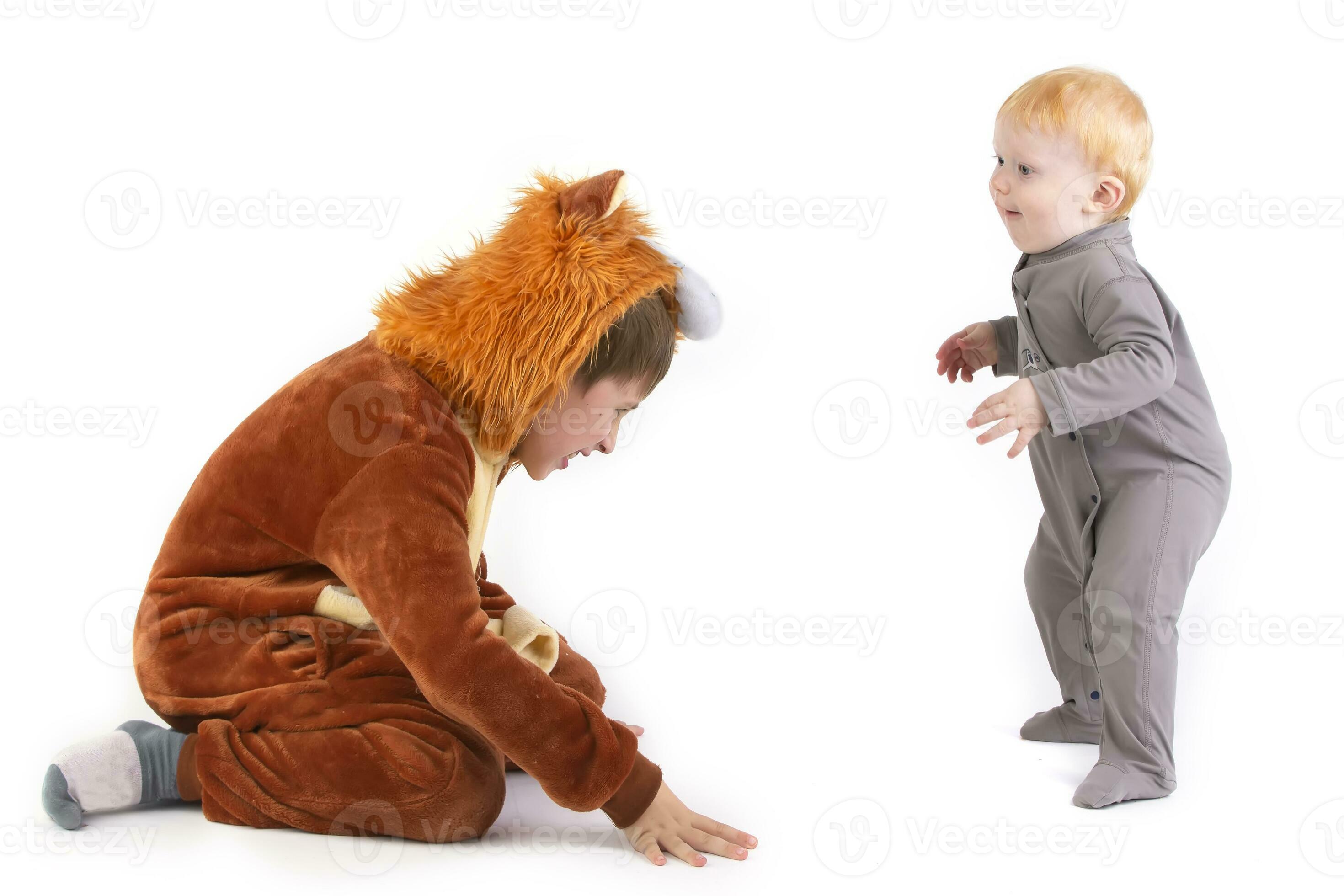 su un' bianca sfondo, il ragazzo giochi con il suo fratello, vestito nel  un' carnevale Leone costume. Sambuco e minore fratello giocare a.  divertente bambini. 24083112 Stock Photo su Vecteezy