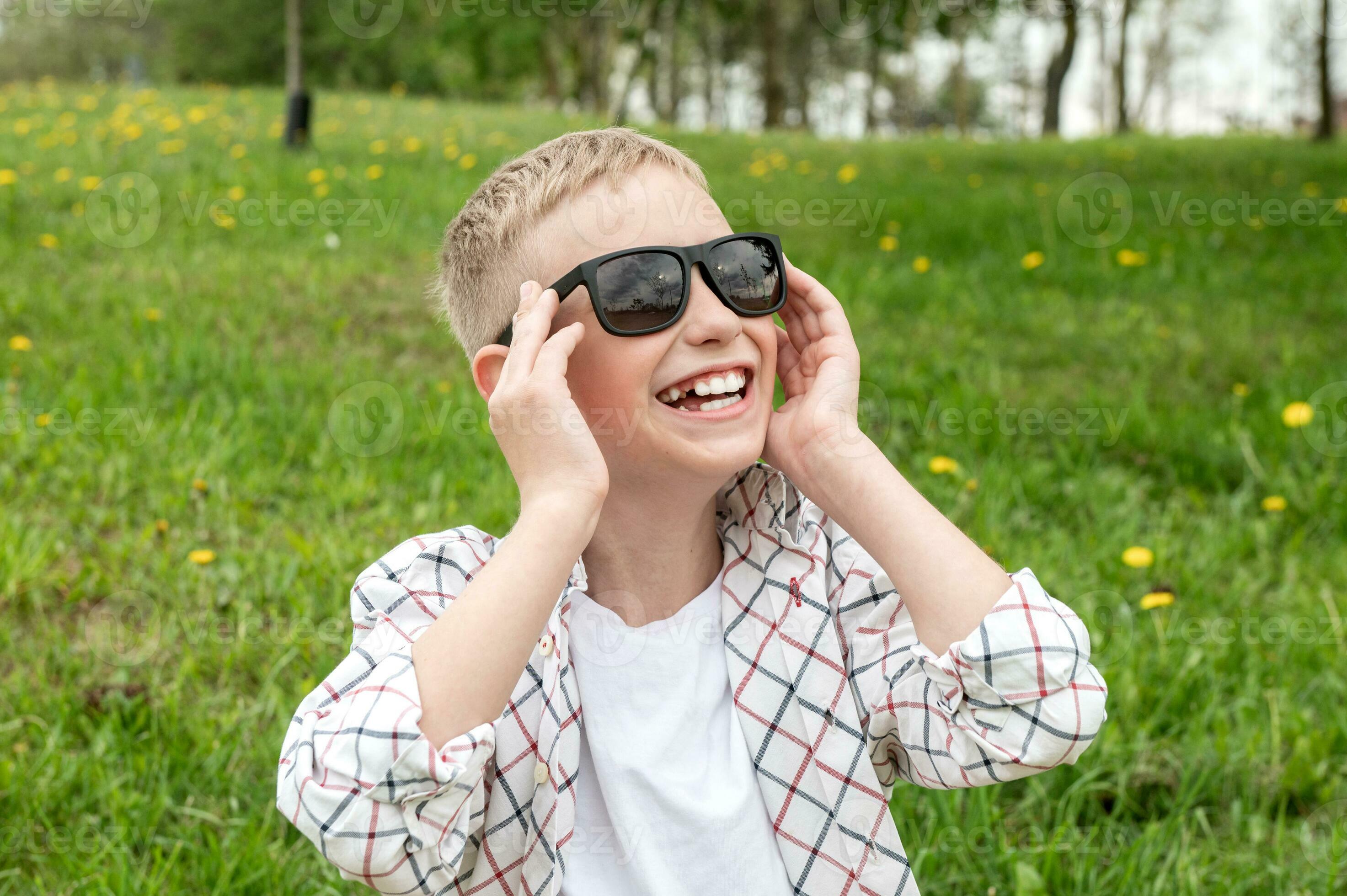 carino ragazzo mettere su daltonico occhiali da sole e ride. bianco