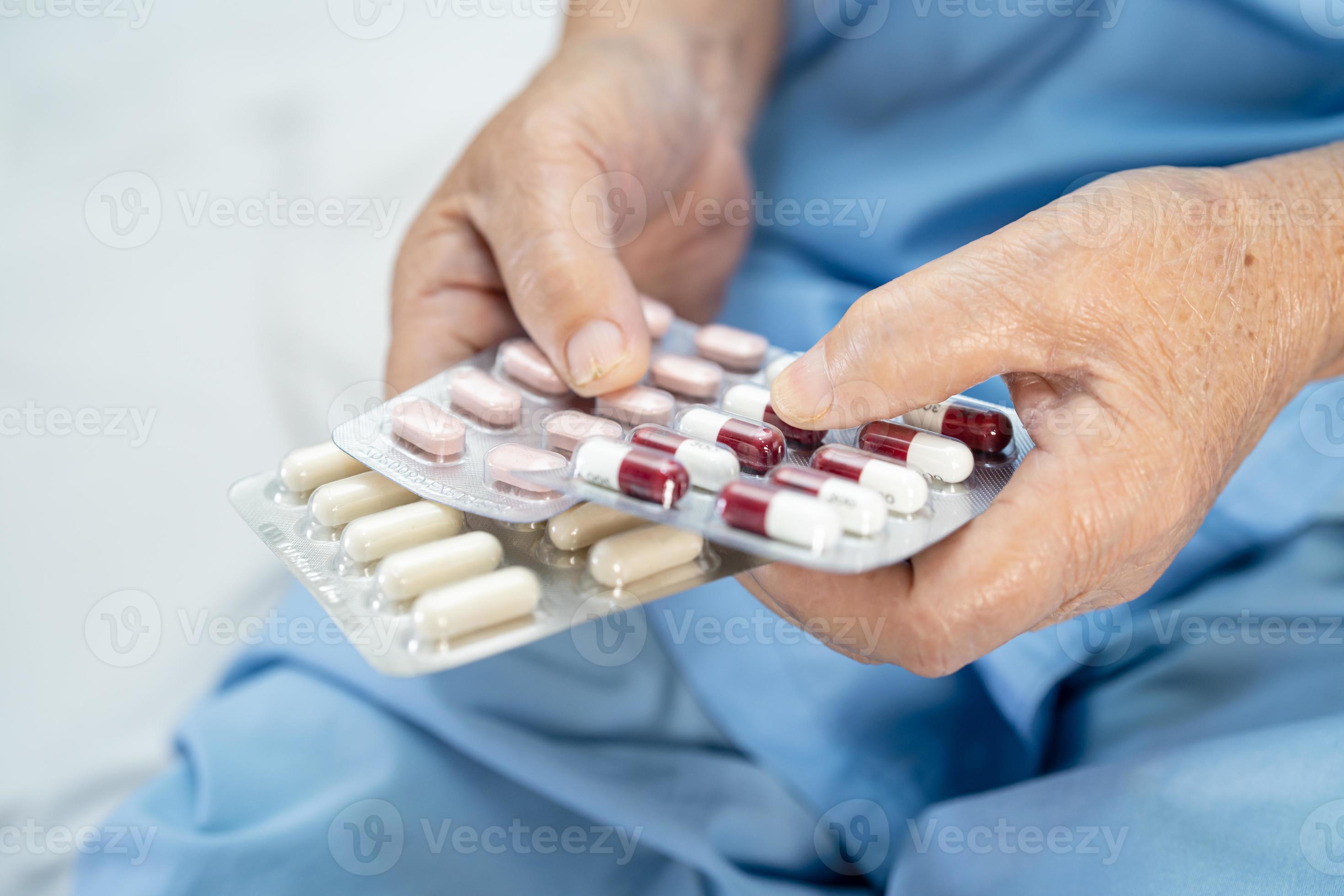 paziente asiatico anziano o anziano della donna anziana che tiene le pillole della capsula degli antibiotici in confezione blister per il trattamento del paziente infezione in ospedale foto