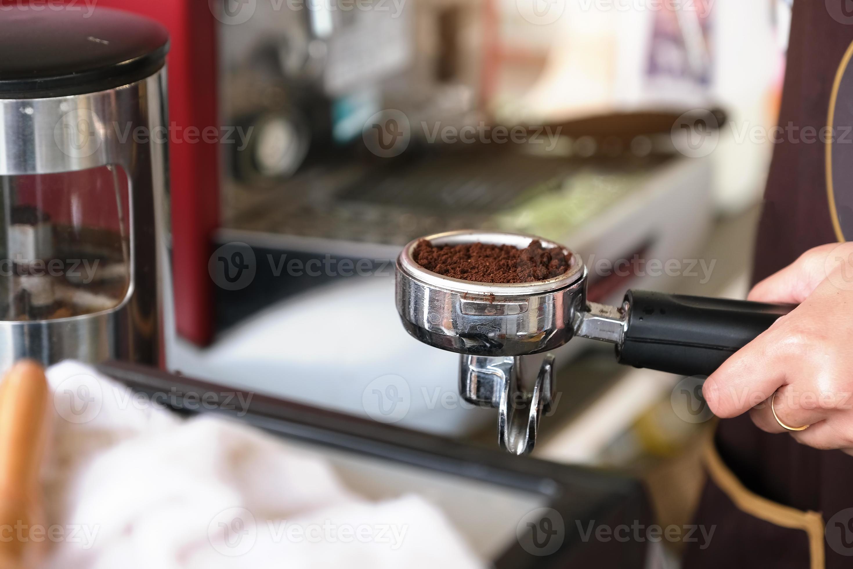 una lavoratrice preme i chicchi di caffè finemente macinati contro un tamper  2883189 Stock Photo su Vecteezy