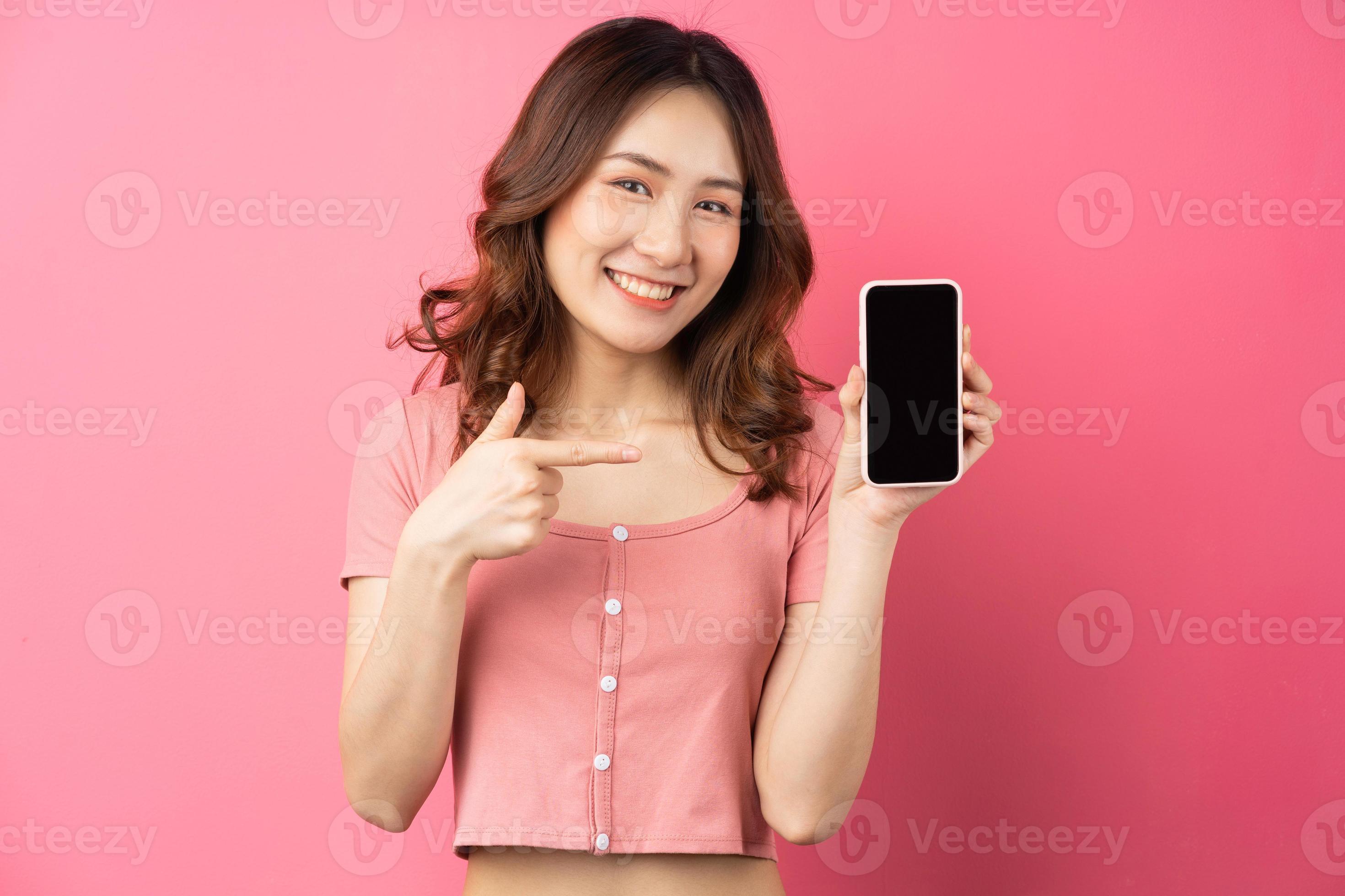 giovane donna asiatica che usa il telefono su sfondo rosa foto