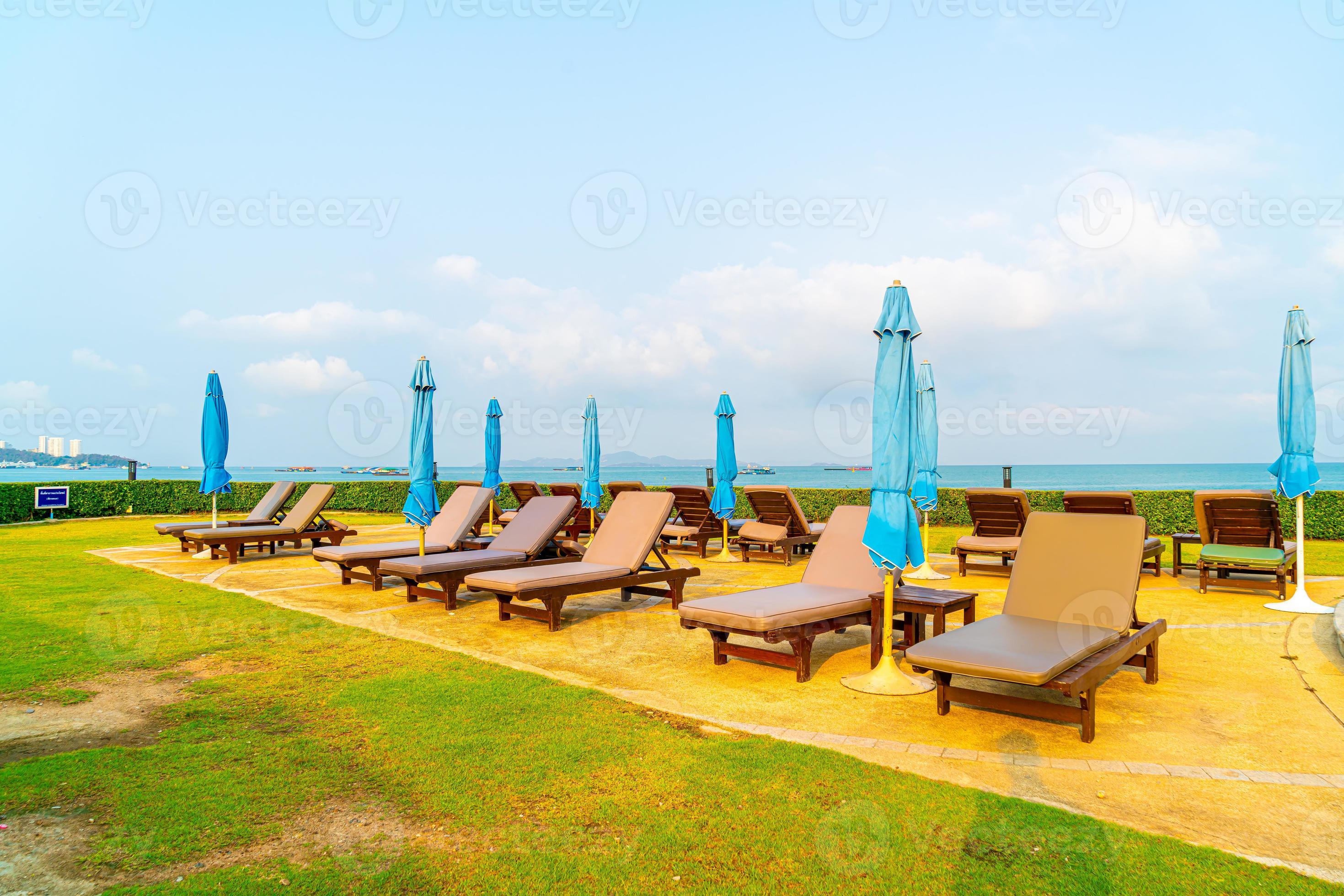 sedia piscina e ombrellone intorno alla piscina con sfondo mare oceano foto