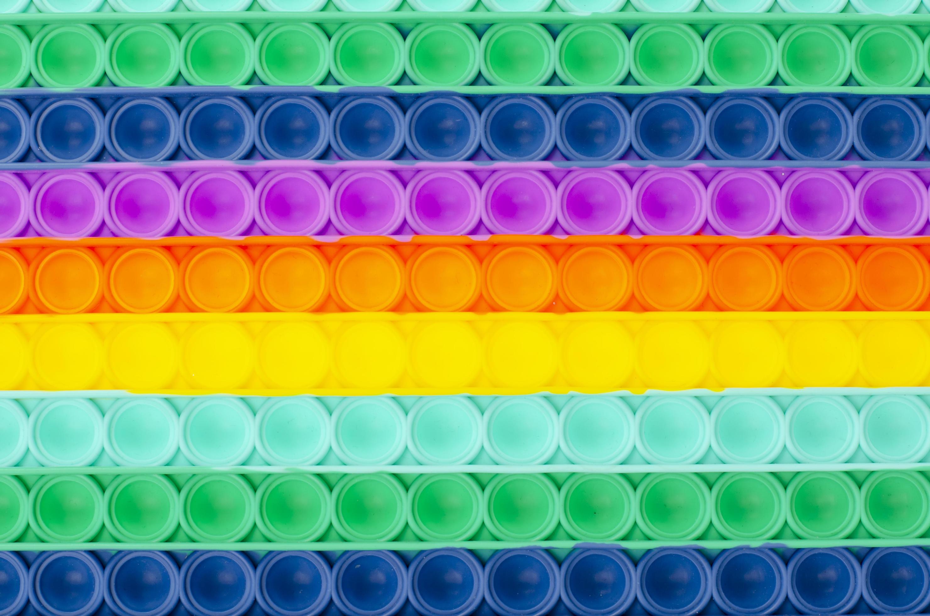sfondo di semplice fossetta colorata arcobaleno pop it. giocattolo antistress alla moda e moderno per bambini e adulti foto