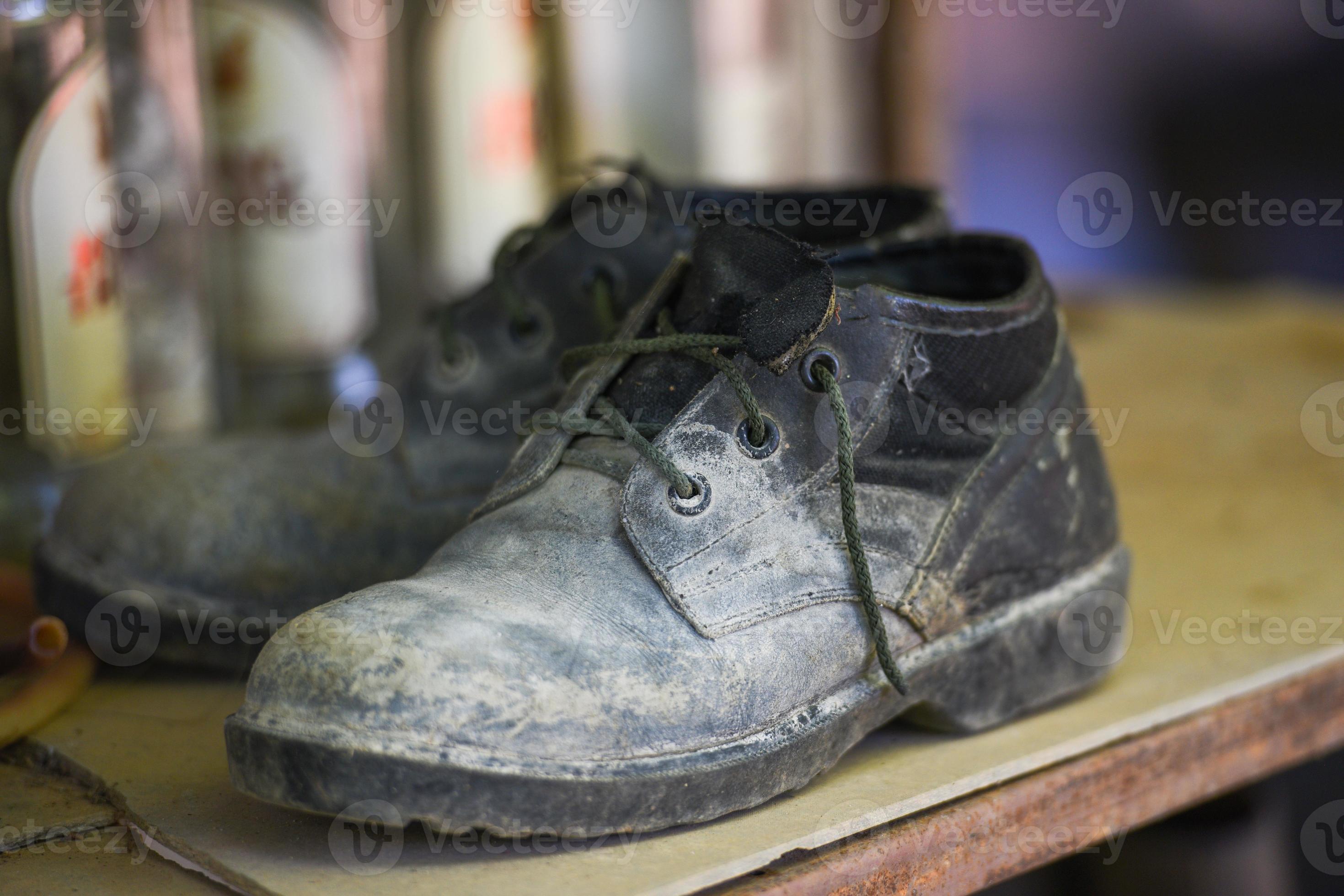 vecchi stivali, scarpe nere sporche sulla scarpiera, stivali