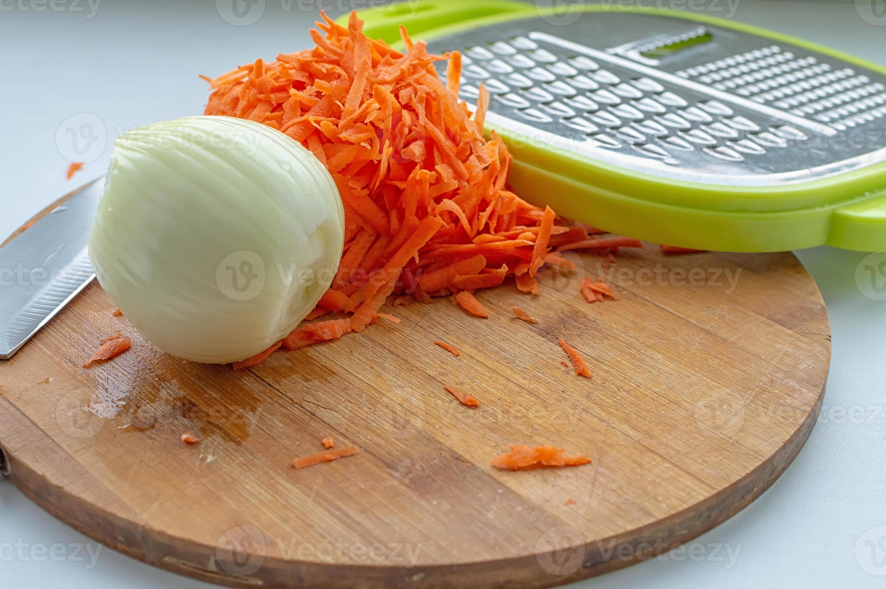 cipolle sbucciate, carote grattugiate e una grattugia su un