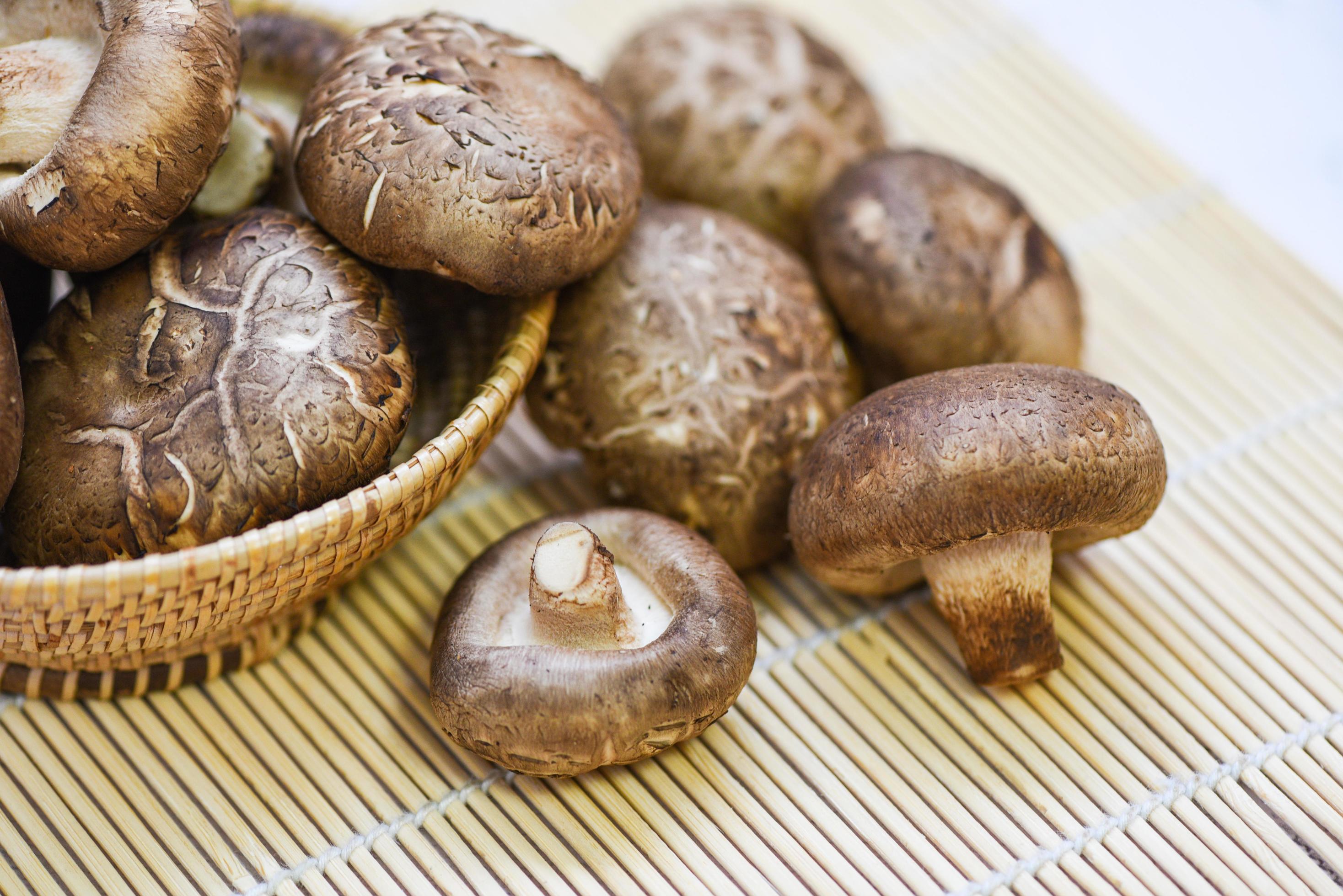 funghi freschi sul cesto e sullo sfondo della tavola in legno - funghi shiitake foto