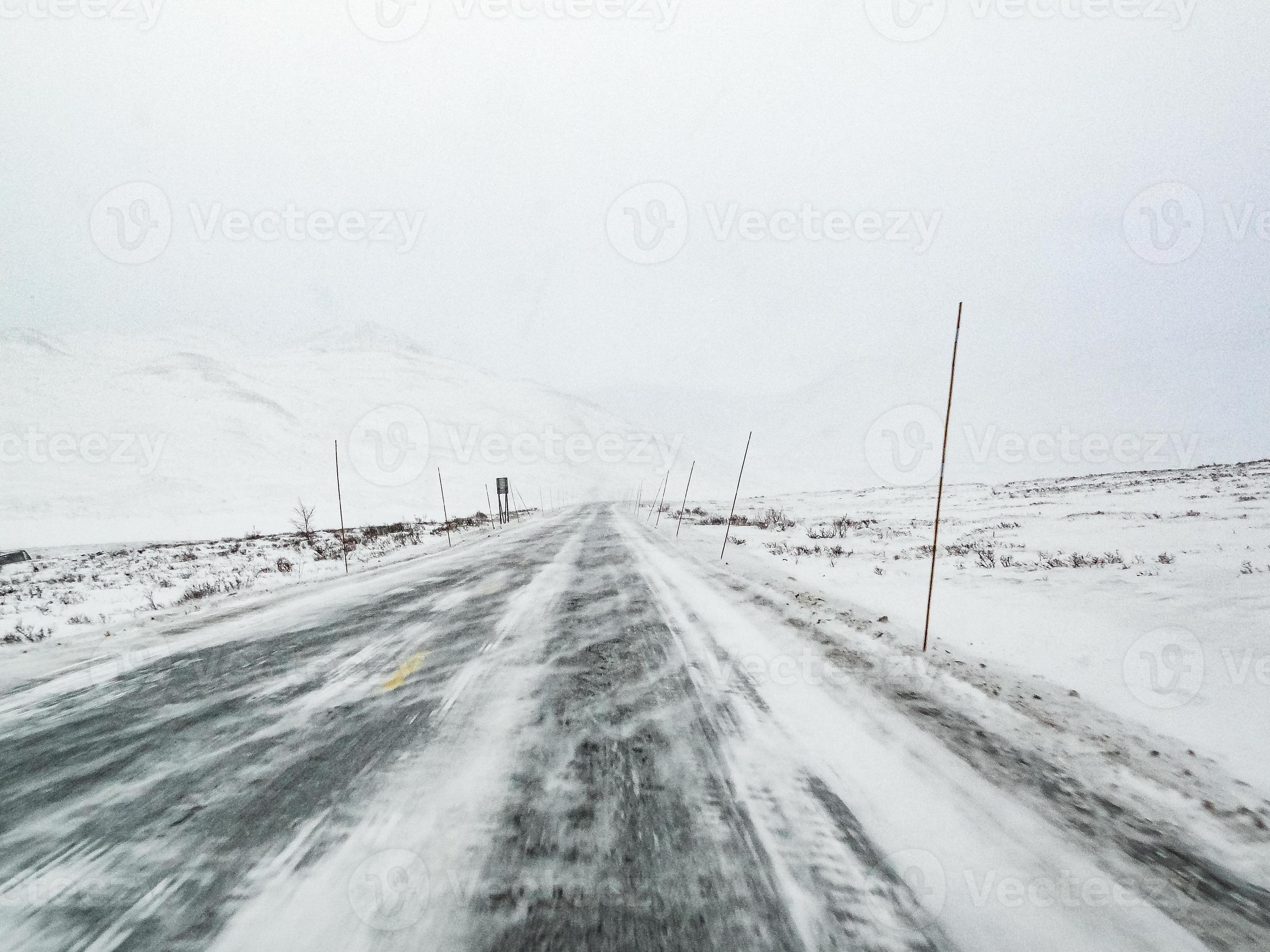 guidando attraverso la tempesta di neve di blizzard con ghiaccio nero sulla strada, norvegia. foto