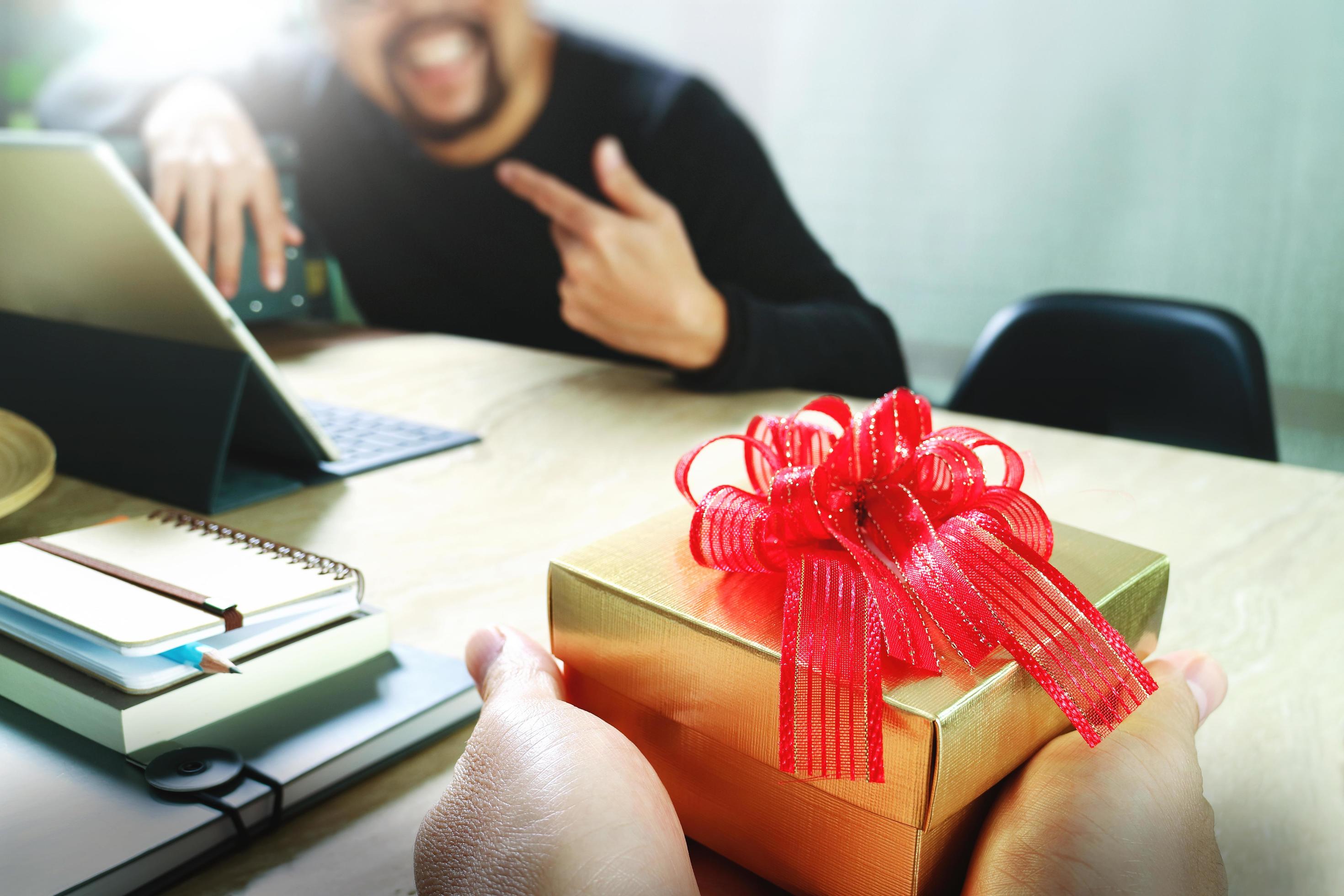 regalo give.business designer creativo mano che dà al suo collega regalo di  Natale in ufficio, effetto film filtro 5289880 Stock Photo su Vecteezy