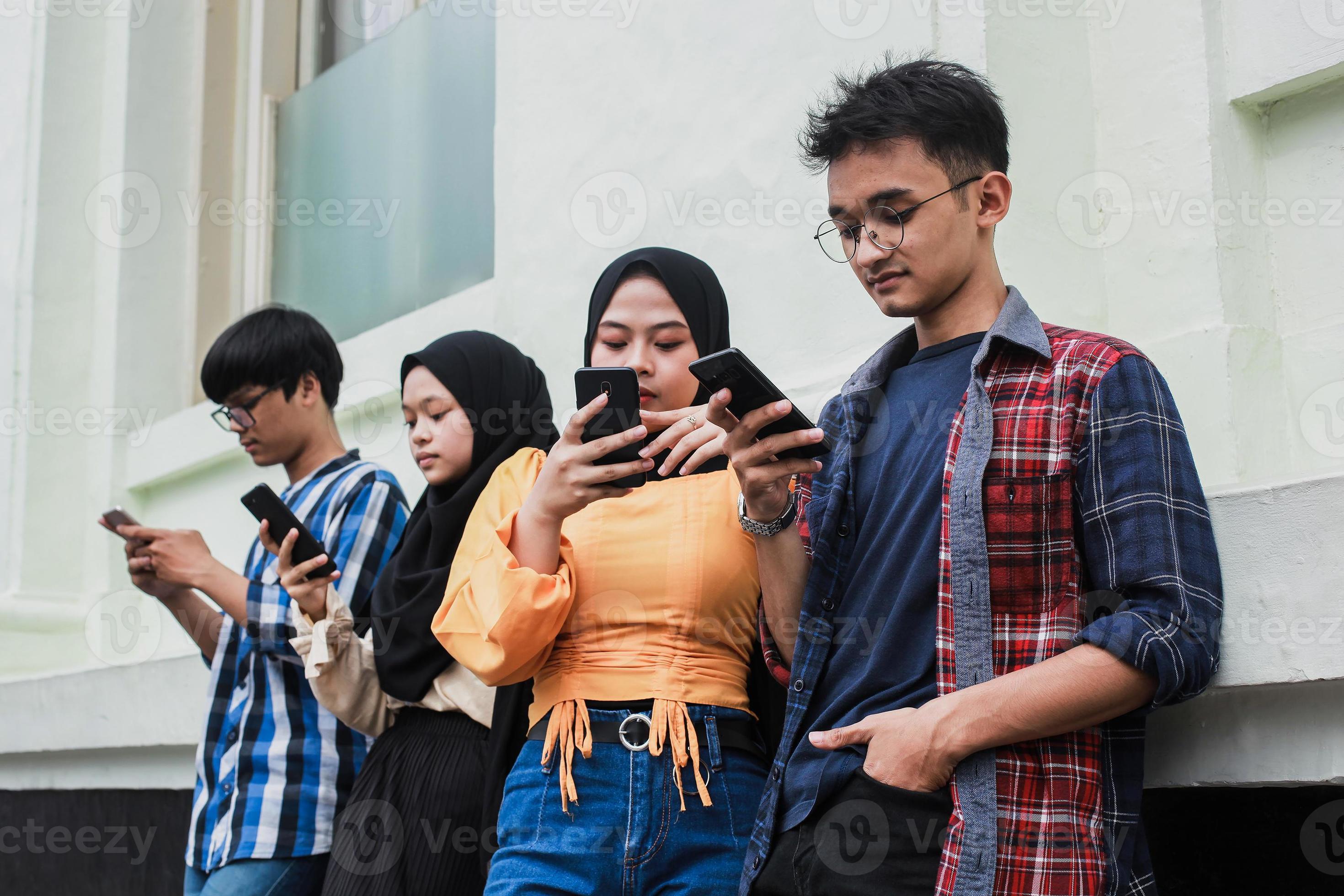 gruppo di amici che guardano telefoni cellulari intelligenti - dipendenza degli adolescenti dalle nuove tendenze tecnologiche - concetto di gioventù, tecnologia, sociale e amicizia foto