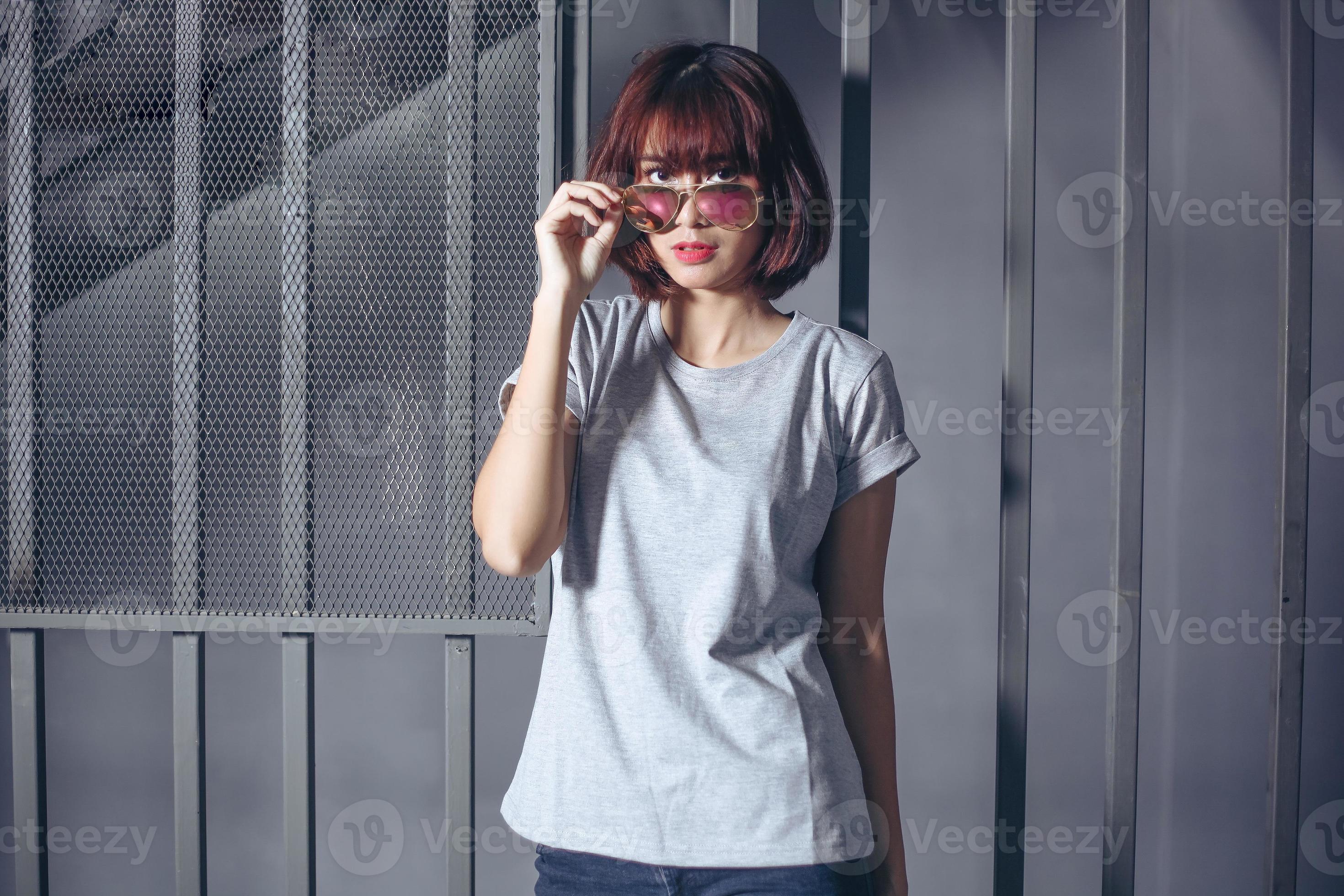 donna alla moda che indossa maglietta grigia e occhiali da sole foto