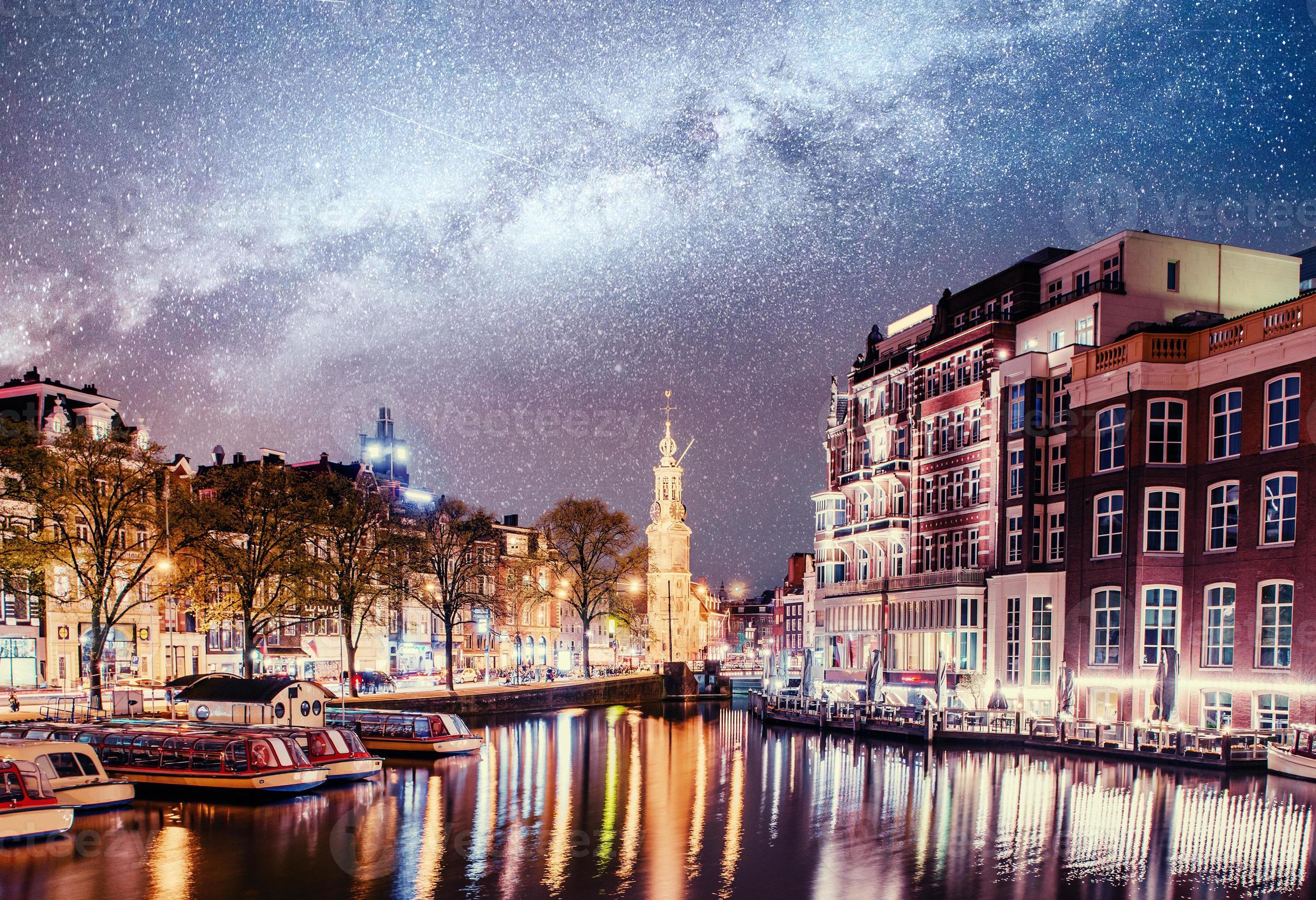 bella notte ad amsterdam. illuminazione notturna di edifici e barche vicino all'acqua nel canale. foto
