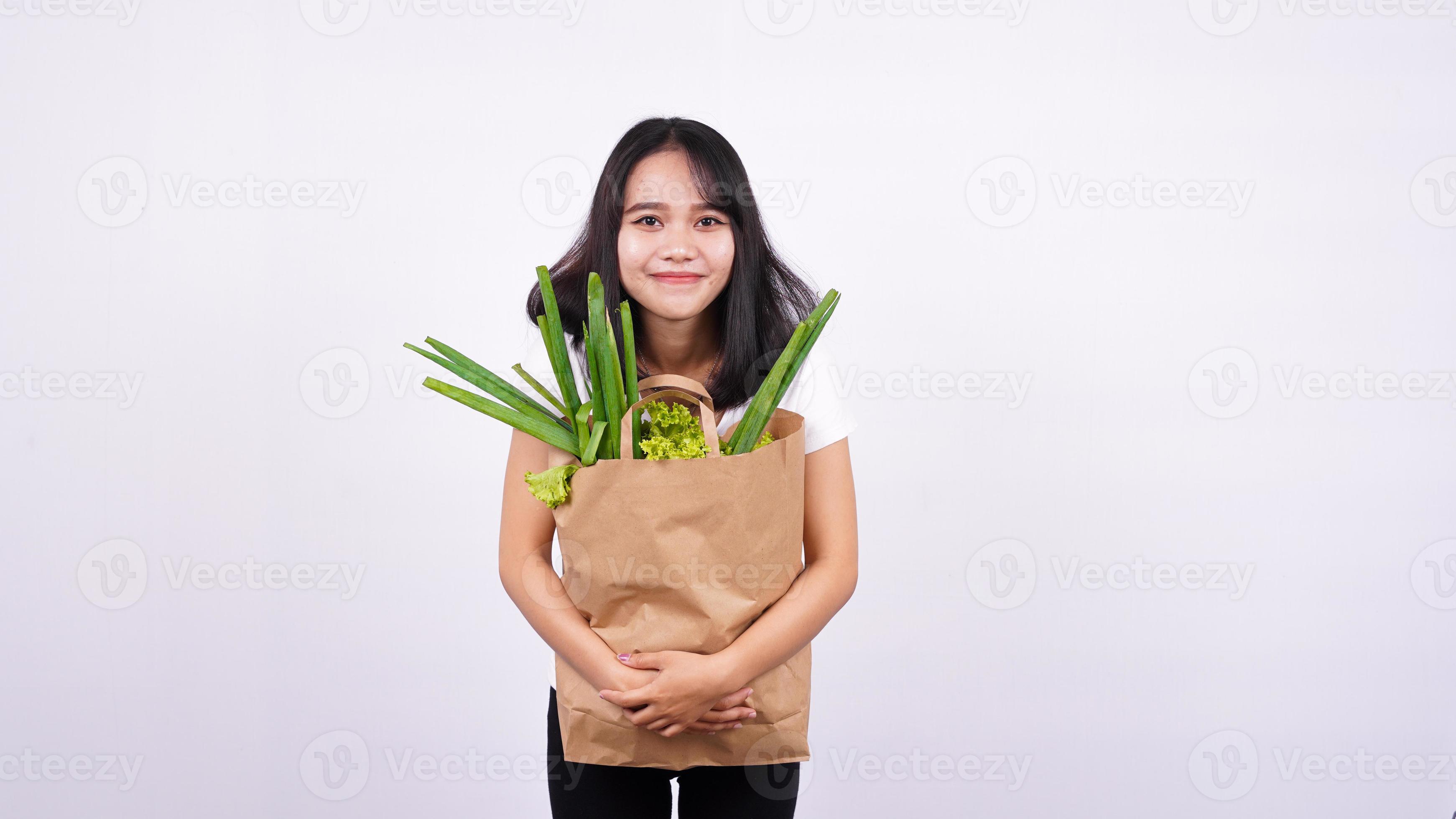 bella donna asiatica sorridente con sacchetto di carta di verdure fresche con sfondo bianco isolato foto