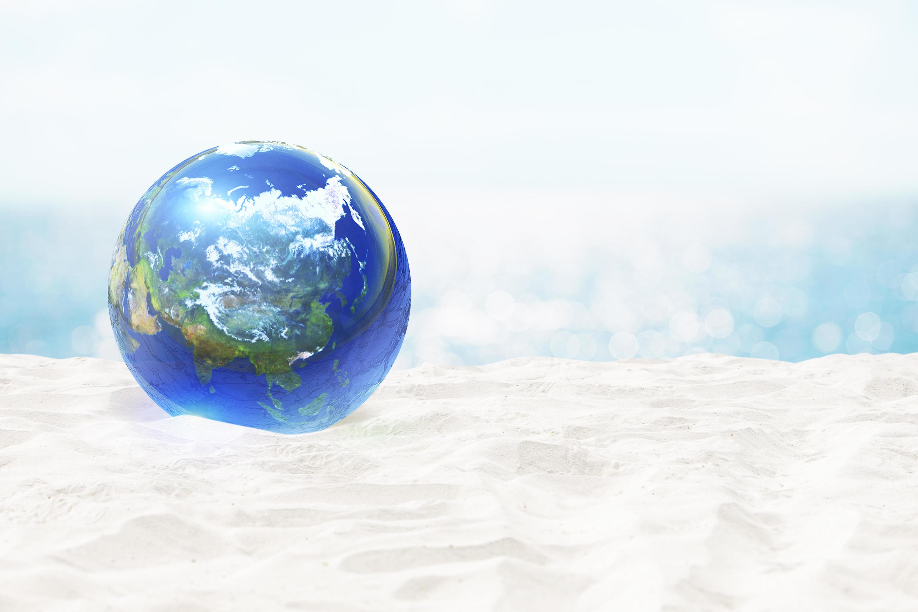 palla di vetro terrestre sulla spiaggia dell'oceano e sulla bellissima spiaggia di sabbia bianca e sfocatura bellissima nuvola sul cielo blu in mare. elementi di questa immagine forniti dalla nasa foto