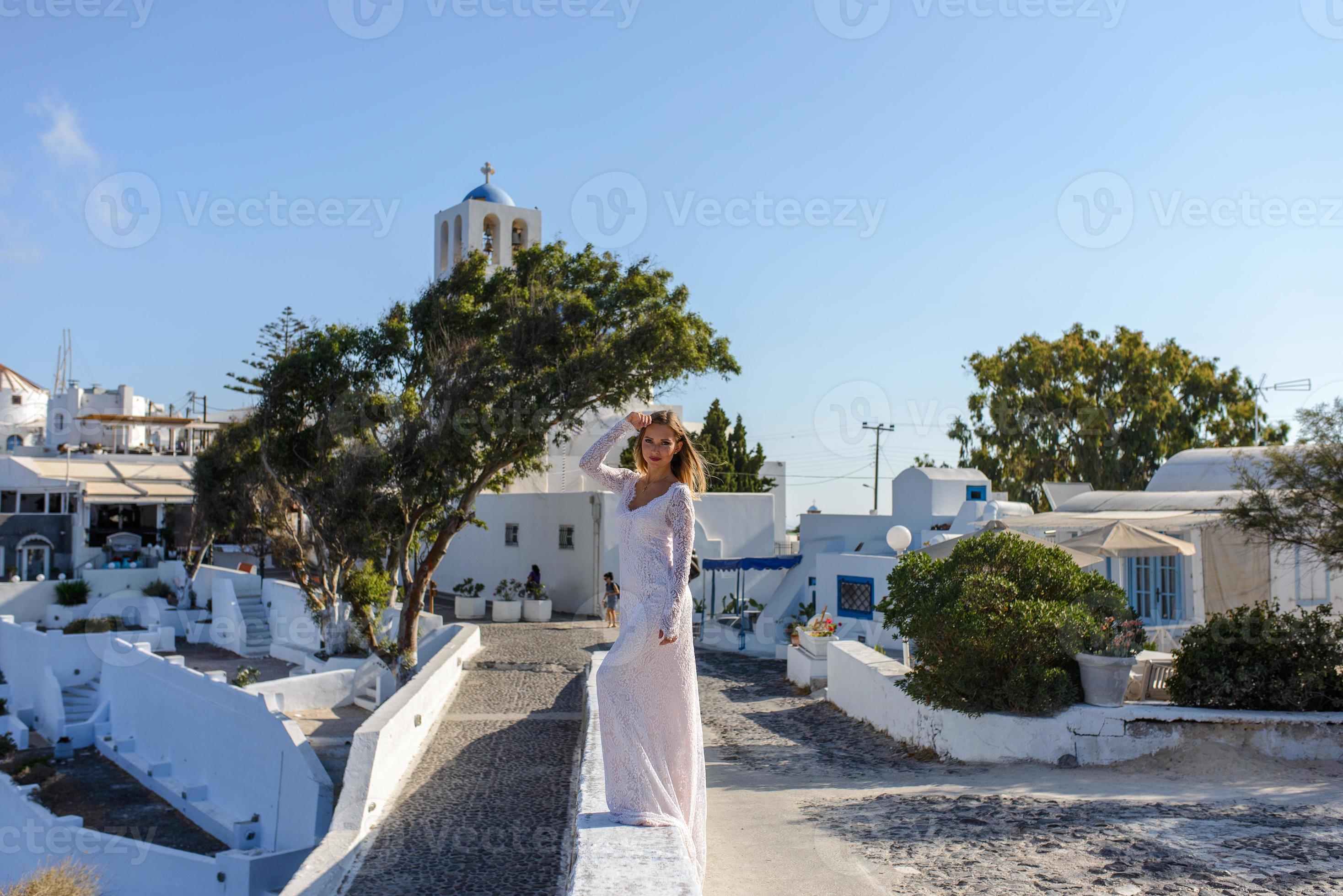 bella sposa in abito bianco in posa sullo sfondo della città di thira, santorini. foto