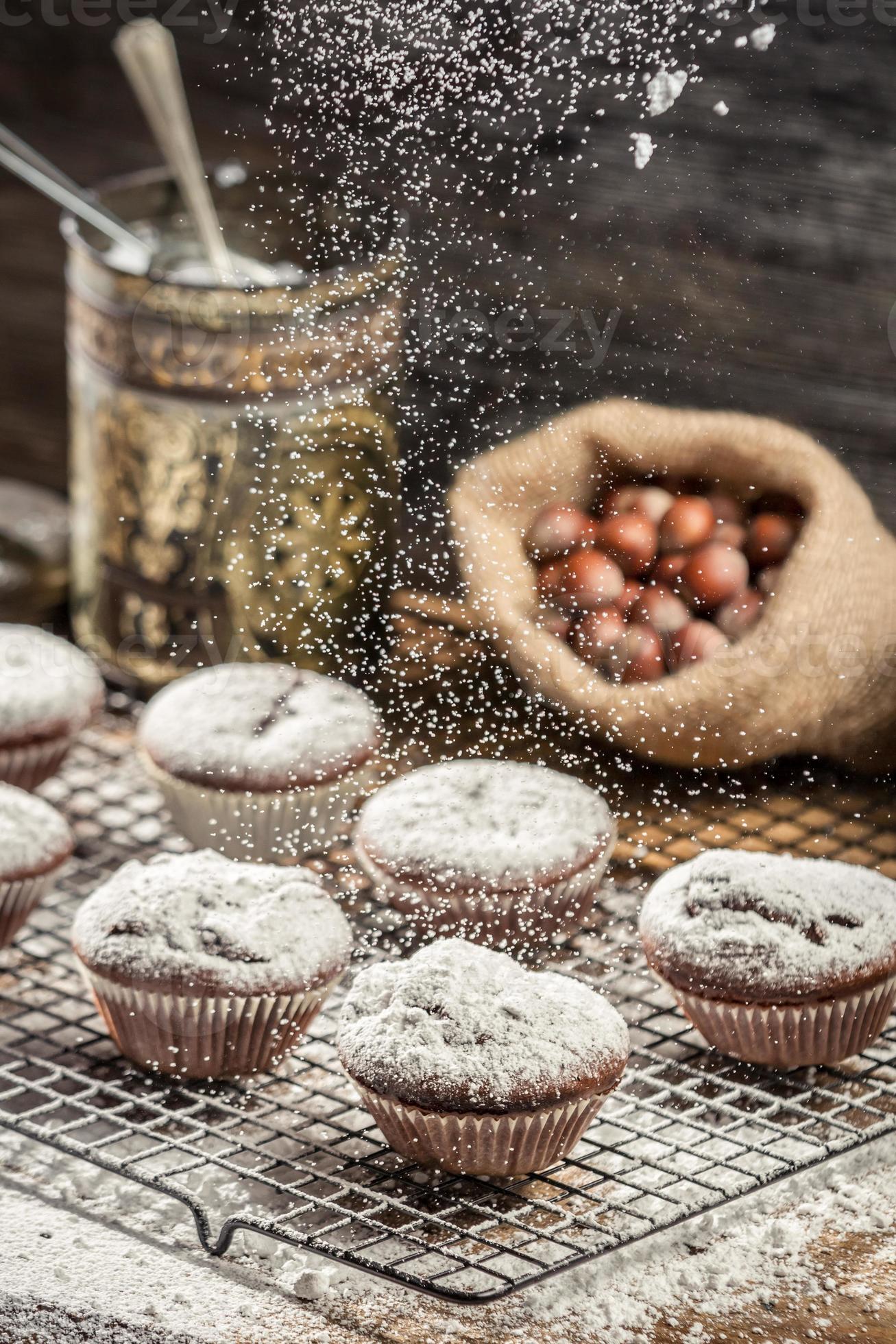 zucchero a velo che cade su muffin al cioccolato fresco foto