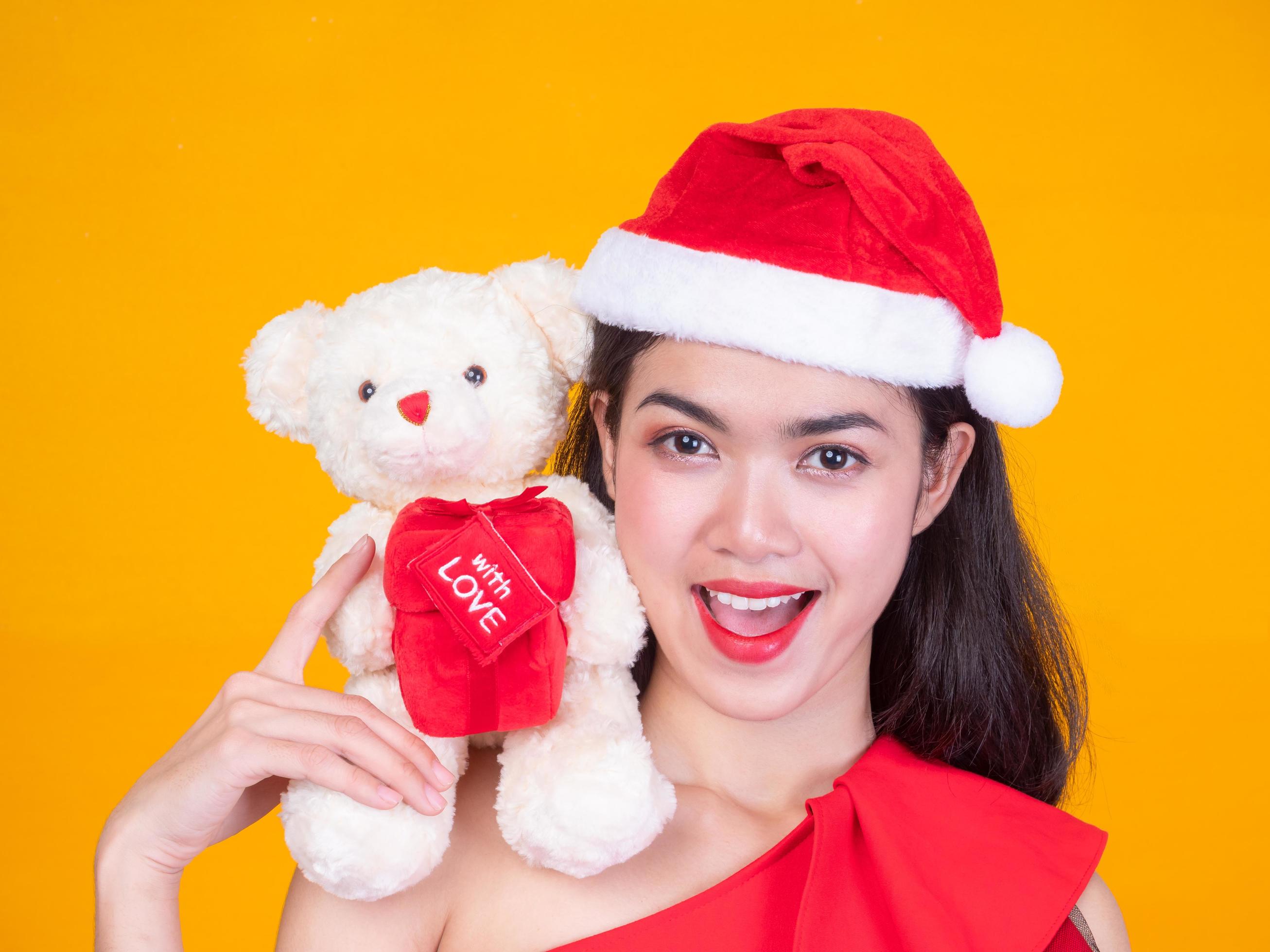 bella ragazza asiatica in costume rosso da Babbo Natale e orso d'amore nel giorno della celebrazione foto