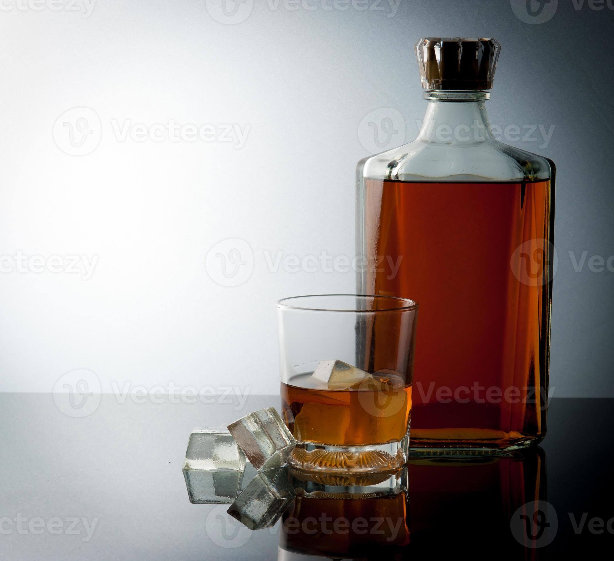 bicchiere e bottiglia con cubetti di ghiaccio foto