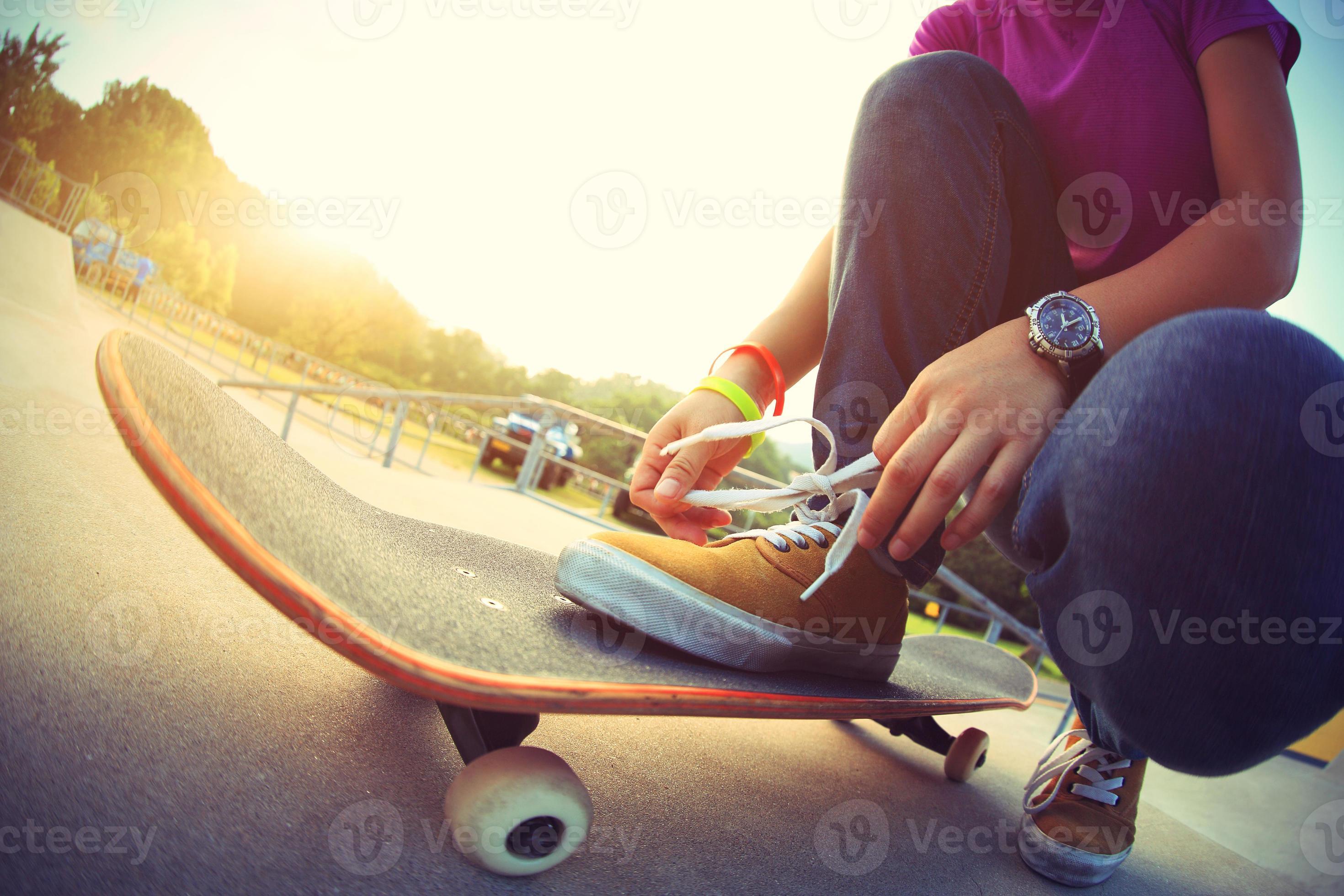 giovane skateboarder asiatico legare i lacci delle scarpe su skateboard foto