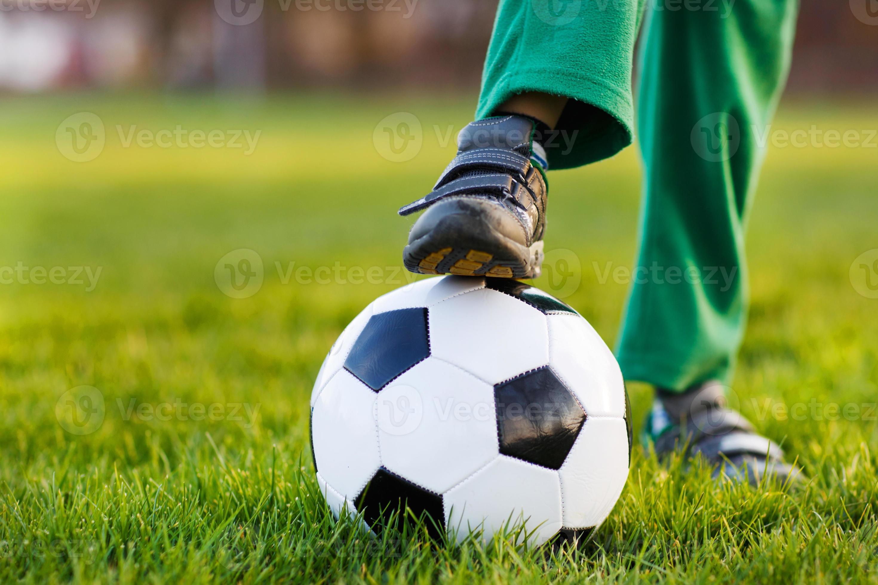 un ragazzo biondo di 4 che gioca a calcio con il campo di calcio onl foto