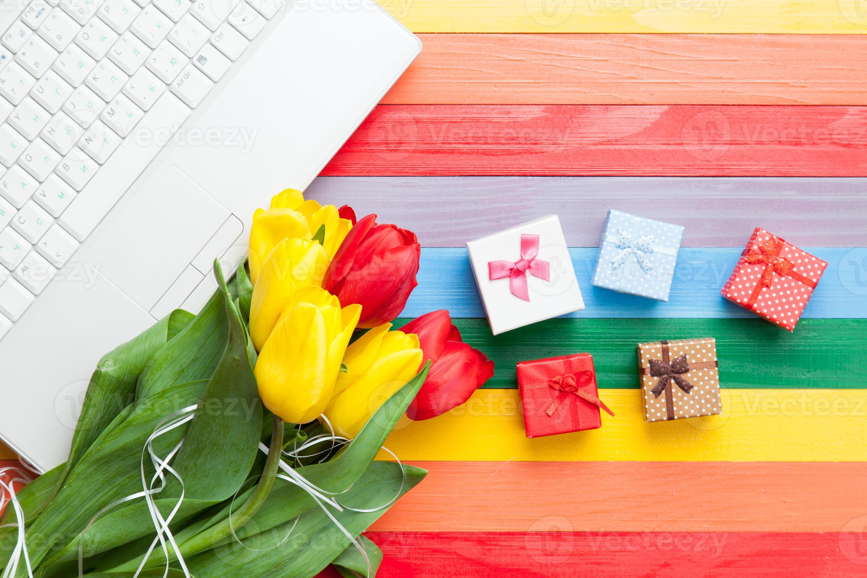 computer bianco e bouquet di tulipani con doni foto