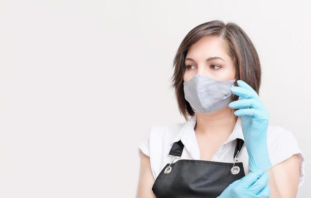 donna che indossa un grembiule che indossa guanti protettivi blu. donna  bruna con maschera tessile su un viso che si prepara a fare la procedura di  bellezza. estetista per la depilazione. 8250911 Stock Photo su Vecteezy