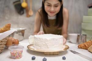 la giovane bella donna sta cuocendo nella sua attività di cucina, panetteria e caffetteria foto