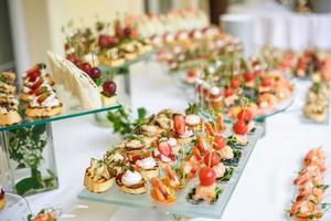 ristorazione. cibo fuori sede. tavolo da buffet con varie tartine, panini, hamburger e snack. foto