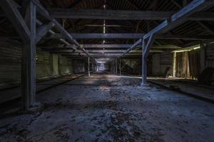 all'interno di un hangar in decomposizione di legno in rovina abbandonato scuro con colonne in decomposizione foto