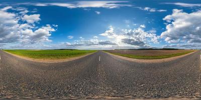 panorama sferico completo senza soluzione di continuità angolo di 360 gradi su strada asfaltata senza traffico tra i campi la sera prima del tramonto con cielo nuvoloso in proiezione equirettangolare, contenuto vr ar foto