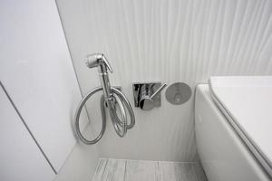 wc e dettaglio di un bidet doccia ad angolo con attacco doccia a parete foto
