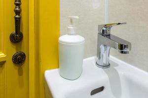 distributori di sapone e shampoo sul lavandino del rubinetto dell'acqua con rubinetto nel costoso bagno a soppalco foto