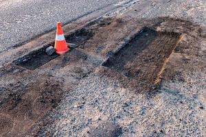 cono di pericolo di traffico arancione bianco sulla riparazione della strada asfaltata foto