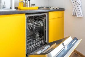interno della cucina moderna con lavastoviglie aperta in appartamento loft in stile minimalista con colore giallo foto