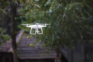 quadrocopter volante bianco con fotocamera su sfondo verde foresta foto