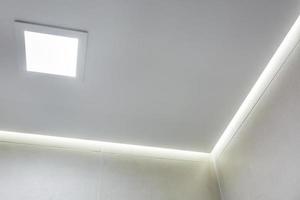 lampade alogene su controsoffitto e costruzione di muri a secco in stanze vuote in appartamenti o case. soffitto teso bianco e di forma complessa. foto