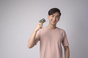 giovane uomo asiatico in possesso di carta di credito su sfondo bianco concetto di studio, shopping e finanza. foto