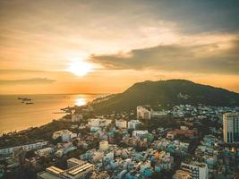 vista aerea della città di vung tau con un bel tramonto e tante barche. vista panoramica costiera di vung tau dall'alto, con onde, costa, strade, palme da cocco e montagna tao phung in vietnam.