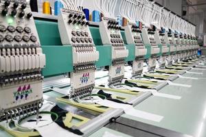 macchina da cucire moderna e automatica ad alta tecnologia per il processo di produzione di abbigliamento tessile o abbigliamento in ambito industriale. industria tessile digitale. ricamo computerizzato. foto