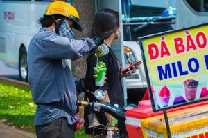 vung tau, vietnam 13 marzo 2022 focus giovane uomo che fa il gelato macinando manualmente il ghiaccio con sciroppo verde. concetto di cibo di strada. ghiaccio tritato di neve con sciroppo di menta e latte condensato zuccherato foto