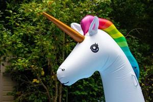 unicorno colorato in plastica contro fogliame scuro foto