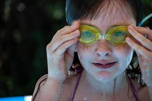 giovane ragazza in occhiali da bagno gialli in piscina foto