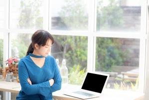 bella del ritratto giovane donna asiatica seduta guardando fotocamera e computer portatile sulla scrivania al bar, computer portatile di lavoro freelance femminile professionale collegare internet lavoro online, concetto di business. foto