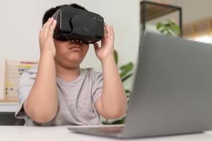 ragazzino asiatico con occhiali vr che studia scienze a casa, uno studente curioso indossa un auricolare per realtà virtuale per studiare scienze a casa studio online stile di vita futuristico apprendimento foto