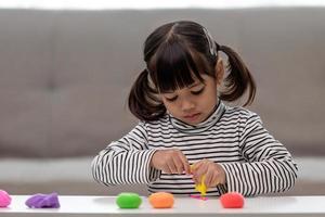 la bambina sta imparando a usare la pasta da gioco colorata in una stanza ben illuminata foto