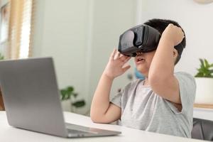 ragazzino asiatico con occhiali vr che studia scienze a casa, uno studente curioso indossa un auricolare per realtà virtuale per studiare scienze a casa studio online stile di vita futuristico apprendimento foto